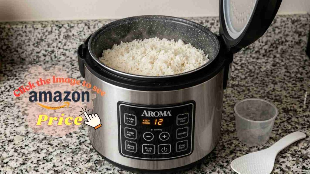 Aroma rice cooker with cooked white rice in bonded granite pot, measuring cup and spatula on counter nearby